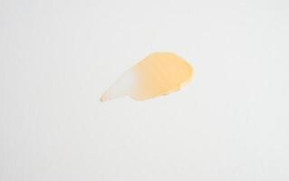 produits cosmétiques texture de tache jaune crémeuse sur fond blanc. la texture des cosmétiques naturels masque capillaire, crème, gommage photo