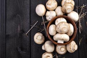 Frais blanc champignons champignon dans bol sur foncé en bois Contexte. Haut voir. copie espace. photo