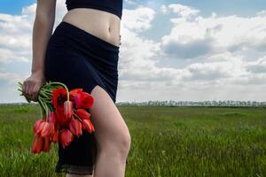 Dame avec une bouquet de tulipes, vue de le jambes et torse. photo