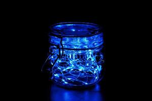bleu Fée lumière dans une verre pot, dans le sombre, discret la photographie photo