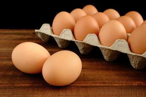 Frais poulet des œufs et Oeuf carton sur vieux foncé marron en bois table dans de face de noir Contexte photo