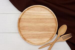 vide rond en bois assiette avec cuillère et fourchette sur blanc en bois tableau. Haut vue image. photo