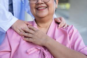 un soignant ou une infirmière asiatique prudente tient la main du patient et encourage le patient en fauteuil roulant. concept de retraite heureuse avec les soins d'un soignant et l'épargne et l'assurance maladie senior. photo