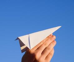 blanc papier avion dans main contre le ciel. une symbole de liberté sur le l'Internet photo