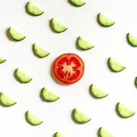 motif répétitif de demi-cercles tranchés de concombres de légumes crus frais pour salade et une tranche de tomate photo