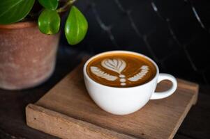 latté art café tasse sur en bois assiette dans foncé Contexte. photo