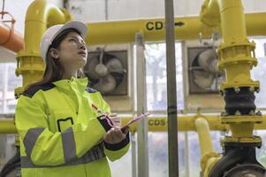 entretien technicien à une chauffage usine, pétrochimie ouvriers superviser le opération de gaz et pétrole pipelines dans le usine, ingénieurs mettre audition protecteur à pièce avec beaucoup tuyaux photo