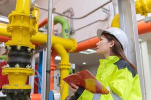 entretien technicien à une chauffage usine, pétrochimie ouvriers superviser le opération de gaz et pétrole pipelines dans le usine, ingénieurs mettre audition protecteur à pièce avec beaucoup tuyaux photo