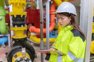 entretien technicien à une chauffage usine, pétrochimie ouvriers superviser le opération de gaz et pétrole pipelines dans le usine, ingénieurs mettre audition protecteur à pièce avec beaucoup tuyaux photo