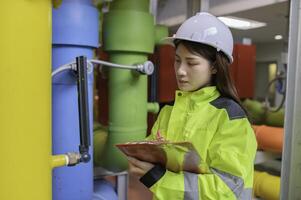 entretien technicien à une chauffage usine, pétrochimie ouvriers superviser le opération de gaz et pétrole pipelines dans le usine, ingénieurs mettre audition protecteur à pièce avec beaucoup tuyaux photo