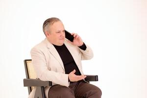 homme séance dans une chaise et parlant sur le téléphone sur une blanc Contexte photo