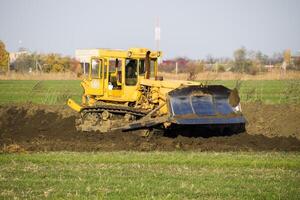 le Jaune tracteur avec attaché grédérom fait du sol mise à niveau. photo