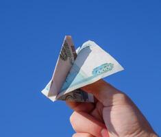 dénominations de russe argent, plié dans le avion contre le bleu ciel dans main photo
