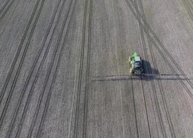 tracteur avec articulé système de pulvérisation pesticides. fertilisation avec une tracteur, dans le forme de un aérosol, sur le champ de hiver blé. photo
