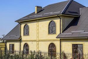 maison de Jaune brique et marron ondulé toit fabriqué de métal. treillis sur le les fenêtres. photo