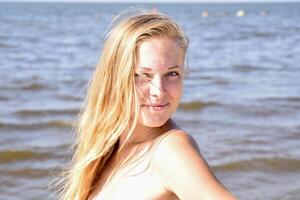 blond fille dans une bikini sur le plage. magnifique Jeune femme dans une coloré bikini sur mer Contexte photo