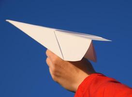 blanc papier avion dans main contre le ciel. une symbole de liberté sur le l'Internet photo