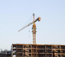 la tour bâtiment grue près le Nouveau maison en dessous de construction. photo