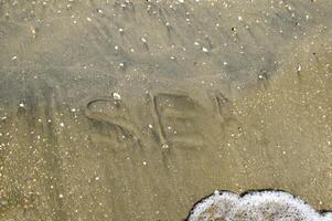 le une inscription de le mer sur le sable. côtier le sable et vagues. les inscriptions sur le rive photo