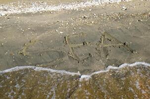 le une inscription de le mer sur le sable. côtier le sable et vagues. les inscriptions sur le rive photo