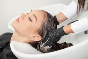 coiffeur la lessive cheveux de une femme dans une beauté salon photo