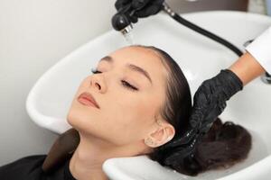 coiffeur la lessive cheveux de une femme dans une beauté salon photo