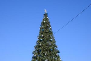 décorations Nouveau année arbre. clinquant et jouets, des balles et autre décorations sur le Noël Noël arbre permanent dans le ouvert air. photo