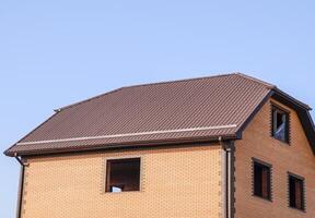 le maison avec Plastique les fenêtres et une toit de ondulé feuille. toiture de métal profil ondulé forme sur le maison avec Plastique les fenêtres photo