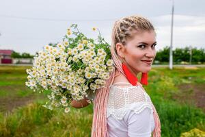 Jeune fille avec une bouquet de marguerites dans champ. marguerites sur une coquelicot champ. photo