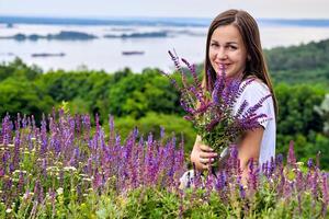 jolie Jeune femme cueillette une bouquet de médical herbes. lilas fleurs et verdure photo