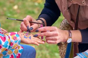 le artiste dessine une coloré papillon sur une enfant main photo