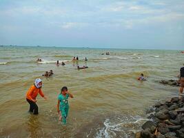 indramayu, Indonésie - janvier 2, 2024 une petit enfant qui a été pleurs car le sien mère Raconté lui à Arrêtez en jouant sur le plage photo