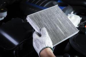voiture air Conditionneur système entretien, main mécanicien en portant voiture air filtre à vérifier pour nettoyer sale ou réparer réparation chaleur avoir une problème ou remplacer Nouveau ou changement filtre. photo
