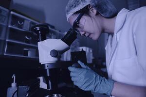 asiatique scientifique travail dans le laboratoire, chercheurs sont recherche à trouver le résultats de le expérience, médecins sont essai sang à prévenir et détruire Nouveau souches de le coronavirus par microscopie. photo