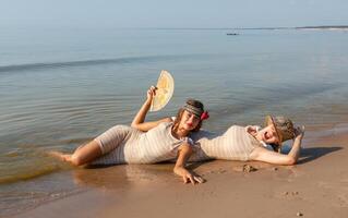 deux Jeune femmes dans rétro maillots de bain par le mer photo