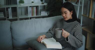 portrait de content Jeune asiatique femme en buvant Matin café ou thé et en train de lire dans vivant pièce à Accueil sur fin de semaine. loisir et style de vie, gratuit temps photo