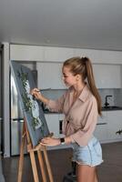 une Créatif femelle artiste des stands et travaux sur une peinture. une content Jeune Dame est La peinture sur Toile dans sa appartement. le concept de une Jeune de la mère loisir photo