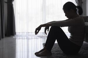 silhouette de une la personne Souffrance de la dépression dans le loger, déprimé femme séance seul sur le canapé ressentir stress, triste et inquiet dans le foncé chambre. la personne sont stressé. photo