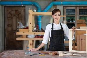 Jeune femme est formation à être une Charpentier dans atelier. Charpentier travail avec équipement sur en bois tableau. femme travaux dans une charpenterie magasin. photo