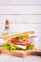 sandwich avec jambon, fromage et oignon sur une en bois planche sur le table verticale vue photo