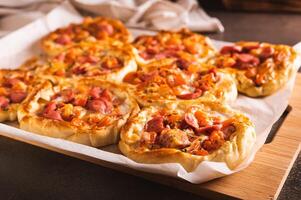 Frais Pizza pot tartes avec tomates, fromage et saucisses sur une en bois planche photo