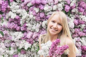 content Jeune femme avec une bouquet sur une Contexte de épanouissement lilas photo