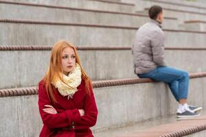 Jeune couple dans une querelle, une gars et une fille sont séance loin de chaque autre dans le vide des stands photo