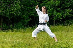adolescent fille formation karaté kata en plein air, effectue âge-uke en hausse ou ascendant bloquer photo