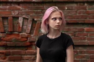 portrait de une adolescent fille avec rose cheveux sur une brique mur Contexte photo