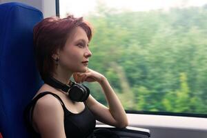 fille monte sur une banlieusard train et regards en dehors le fenêtre à une Naturel paysage flou dans mouvement photo