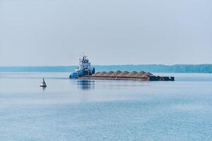 poussoir remorqueur pousse sec masse cargaison barge avec le sable sur le rivière dans le Matin brume photo