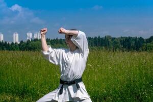 adolescent fille formation karaté kata en plein air, effectue le haïwan uke mouvement photo