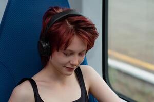 Jeune femme écoute à la musique avec écouteurs tandis que équitation sur une haute vitesse train photo