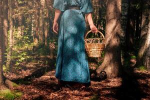 Jeune femme dans populaire paysan vêtements avec une osier panier des promenades dans le foncé forêt photo